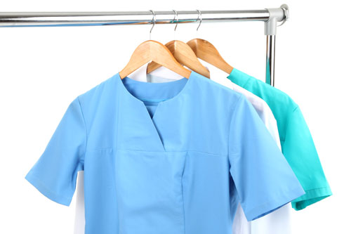 Scrubs and doctor's coat hang on a clothes rail